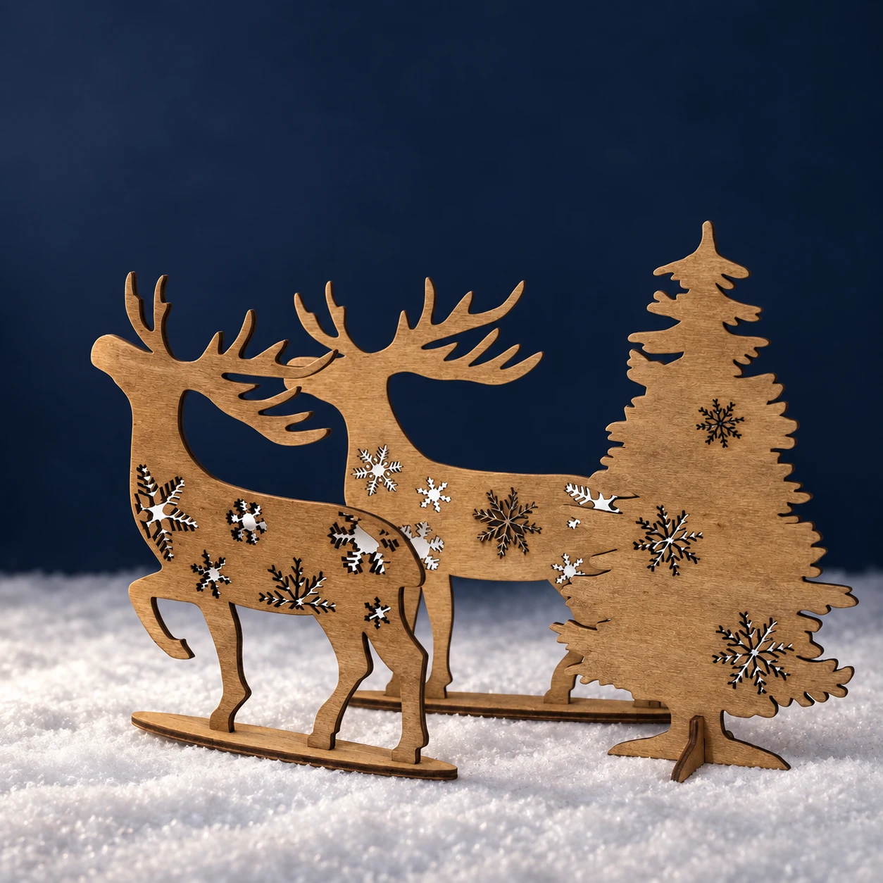 Due renne in legno e un abete con fiocchi di neve su fondo blu